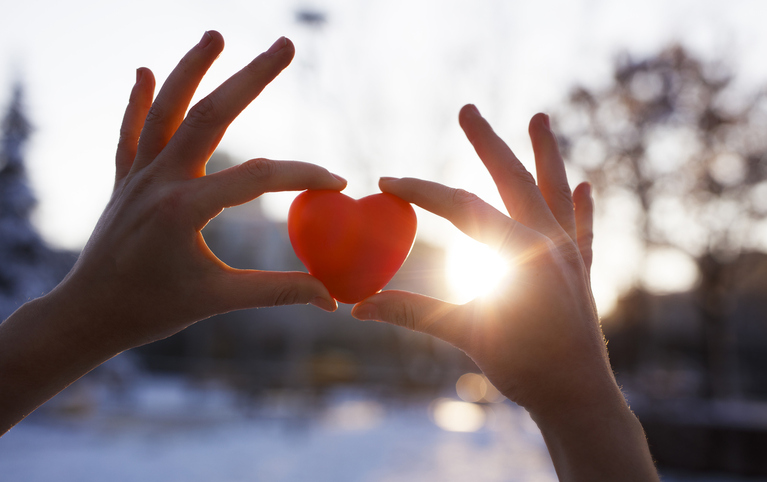 Image of two hands holding a heart with their index finger and thumb.