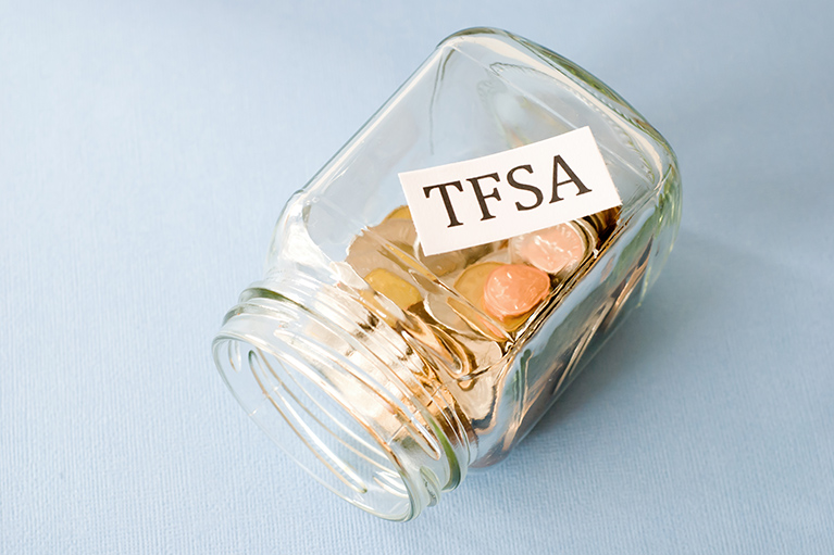 glass jar full of coins on it's side and a label inside stating TFSA
