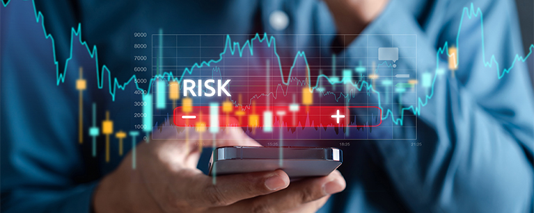 Image of a person holding a smart phone with the word risk placed above and graph placed in the background.