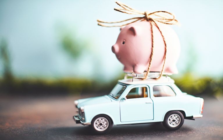 A savings piggy bank tied on top of a toy car.